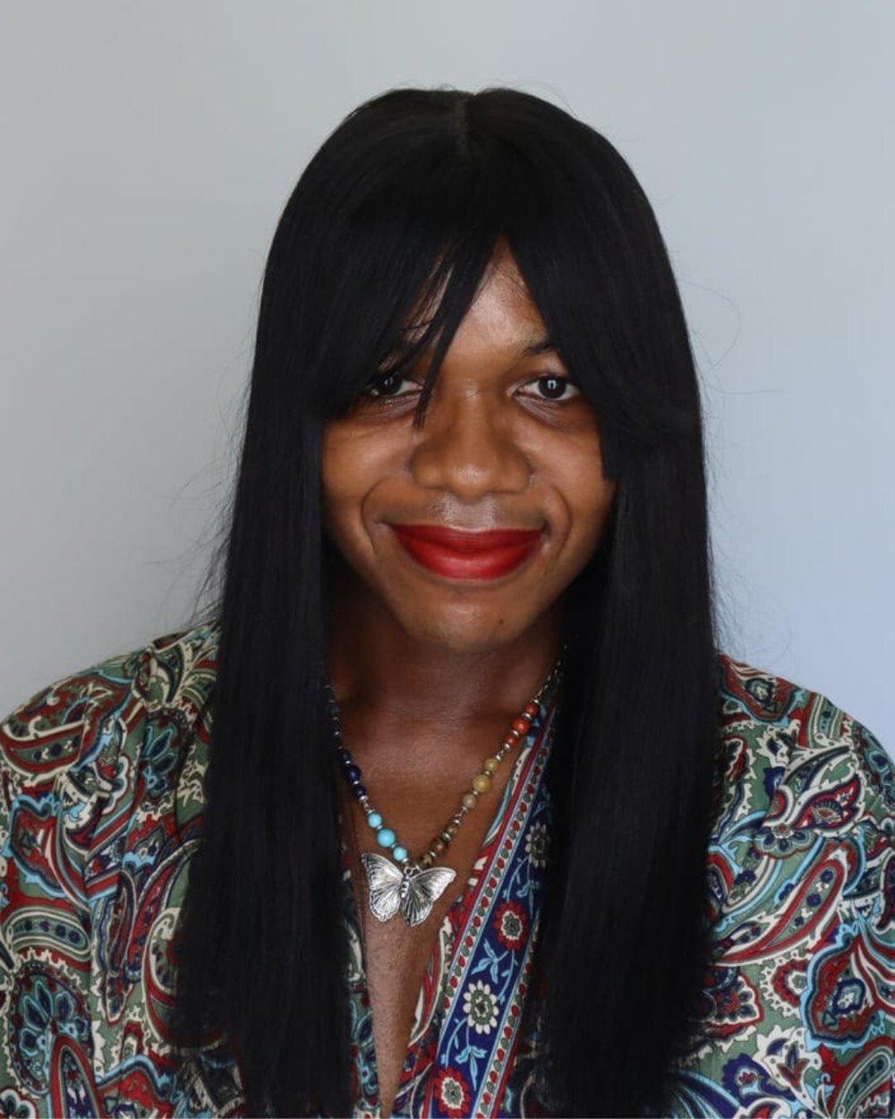 Ayanna wearing a colorful dress and a necklace that has a butterfly pendant.
