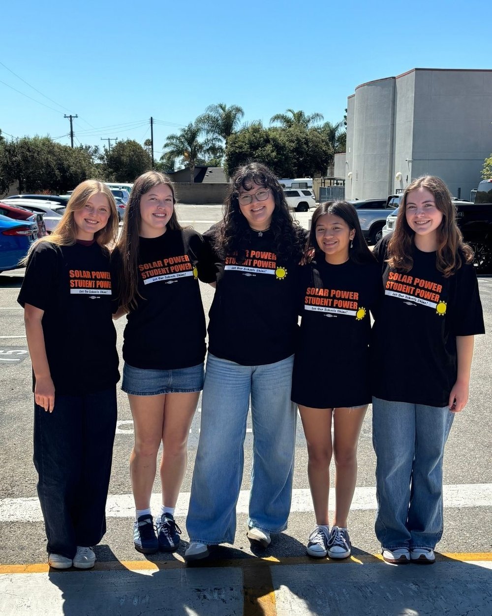 Bea poses with classmates on the schoolyard, with a blue sky in the background.
