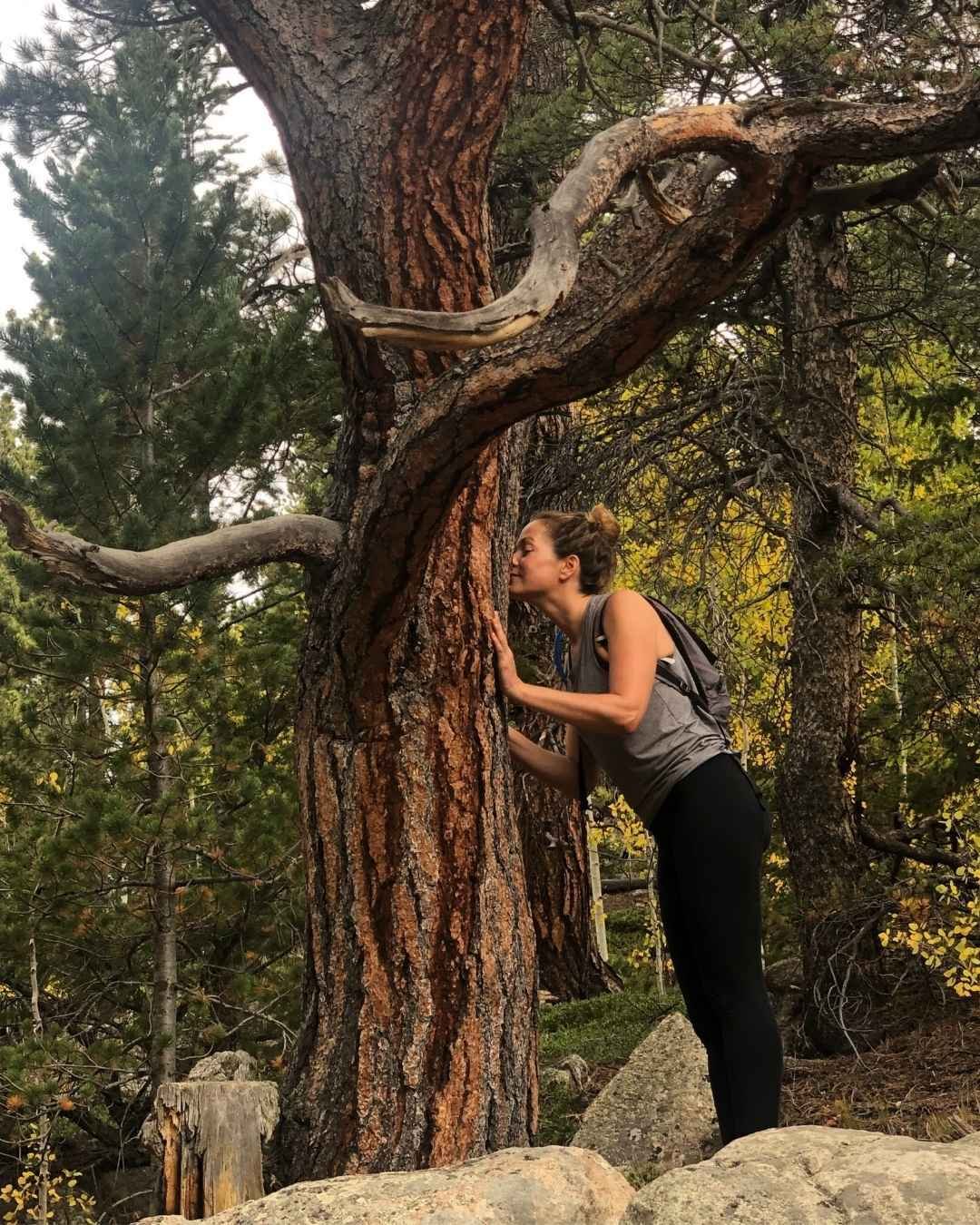 Corinne standing up against a tree, sniffing the bark.