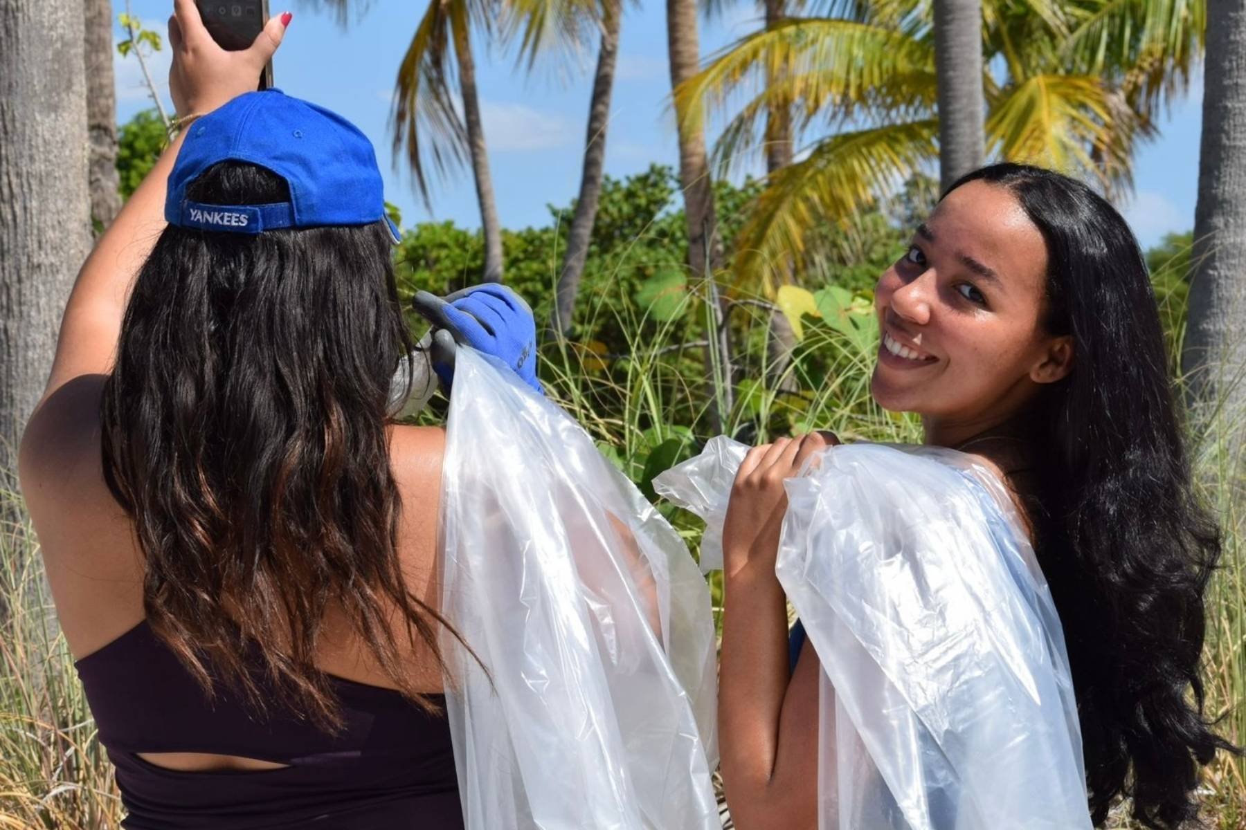 Elianny poses before a beach cleanup, with palm trees in the background.