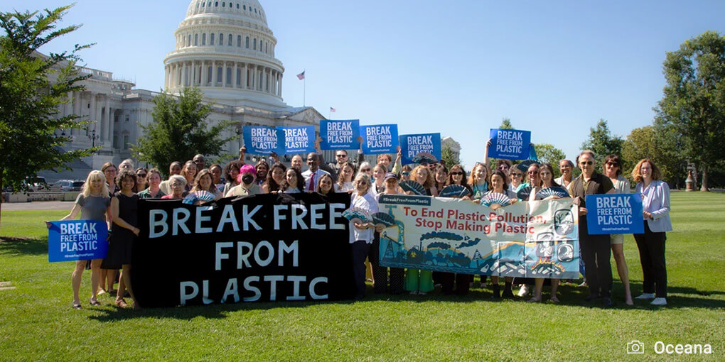 A group with signs reading "Break Free from Plastic" post in front of the Capitol building in Washington DC.