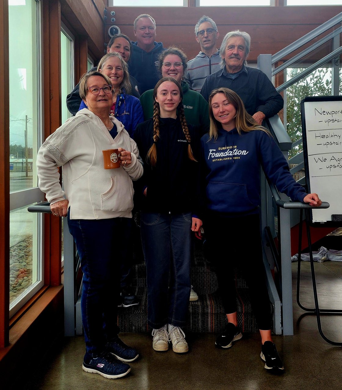 9 people stand on a staircase posing for a photo