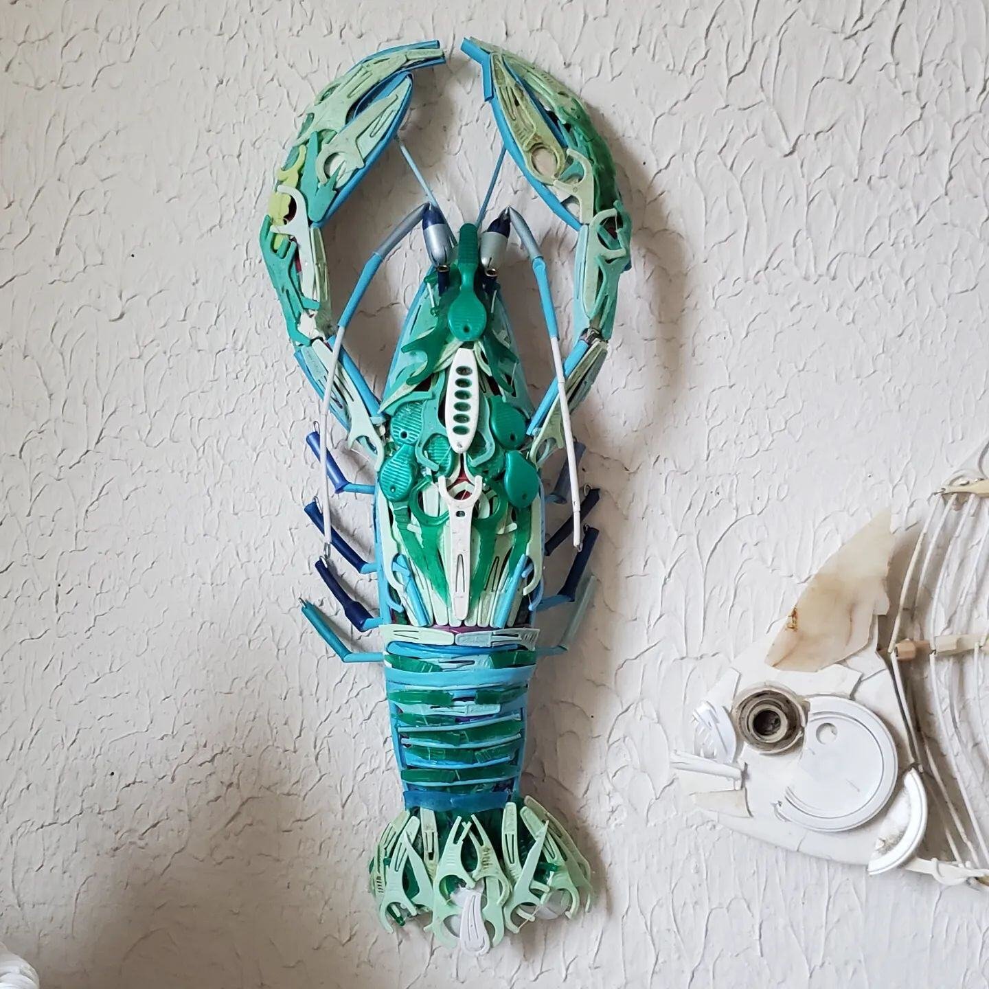 Blue / green lobster made out of small plastic trash items.