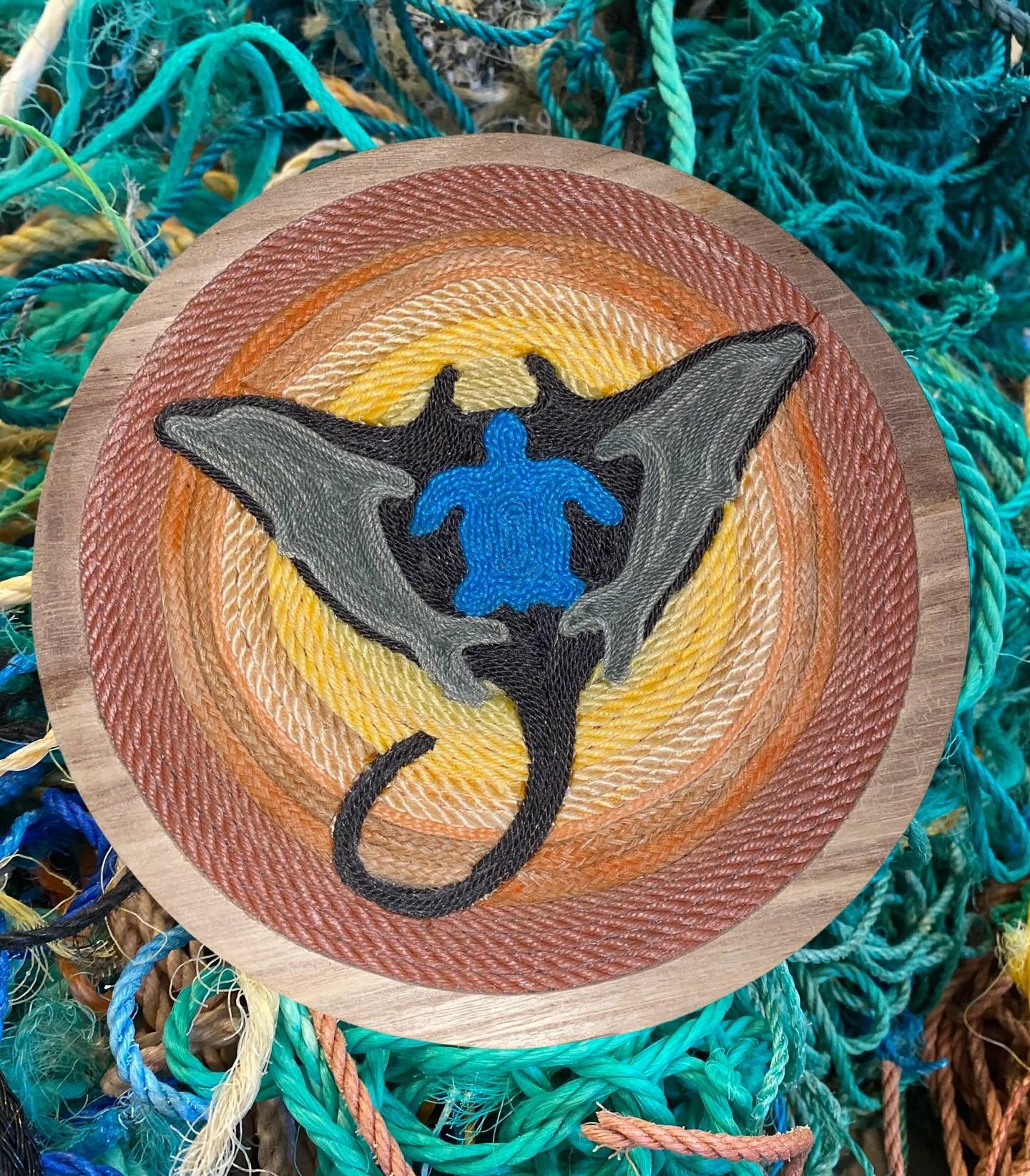 Manta ray with two dolphins on either end and a seaturtle in the middle made out of discarded pieces of colorful rope.