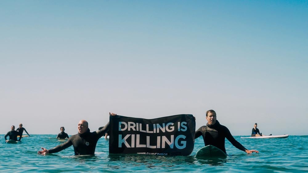 Volunteers hold a Drilling is Killing banner in the ocean at the Paddle Out to Protect Our Coast event at Refugio Beach in California