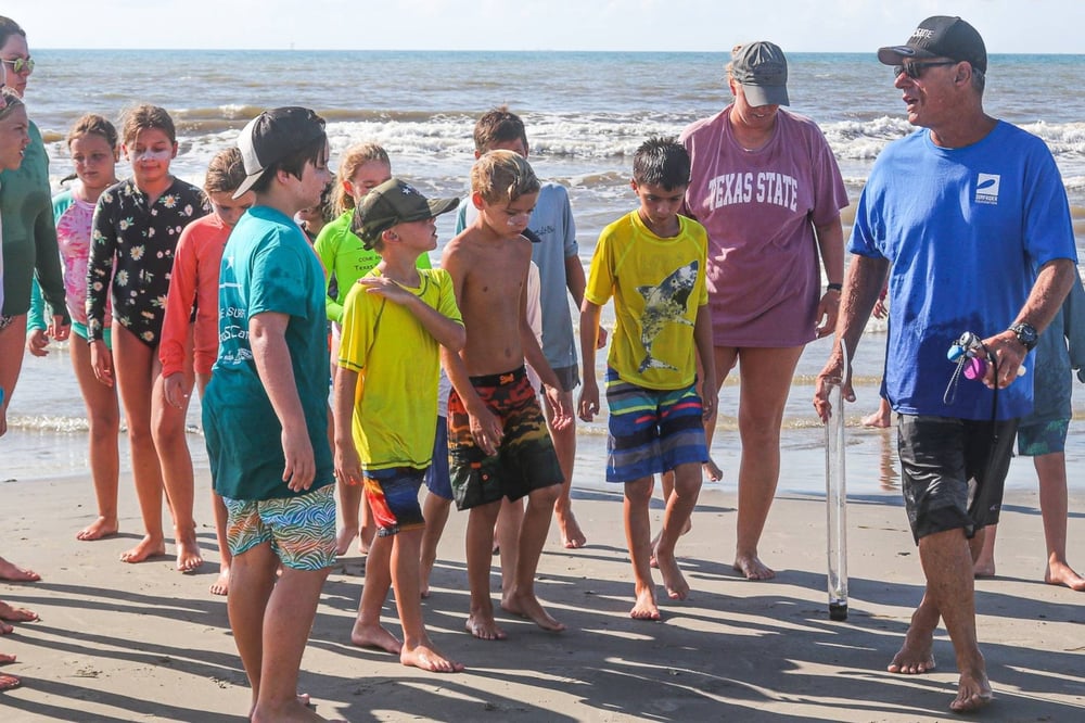 Tommy walks along the beach with a group of local youth as he explains the importance of ocean water quality sampling.