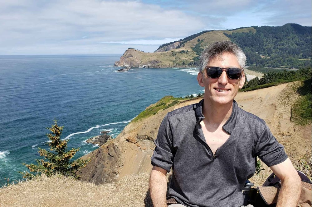 Vince poses in front of a picturesque Pacific Northwest shoreline.