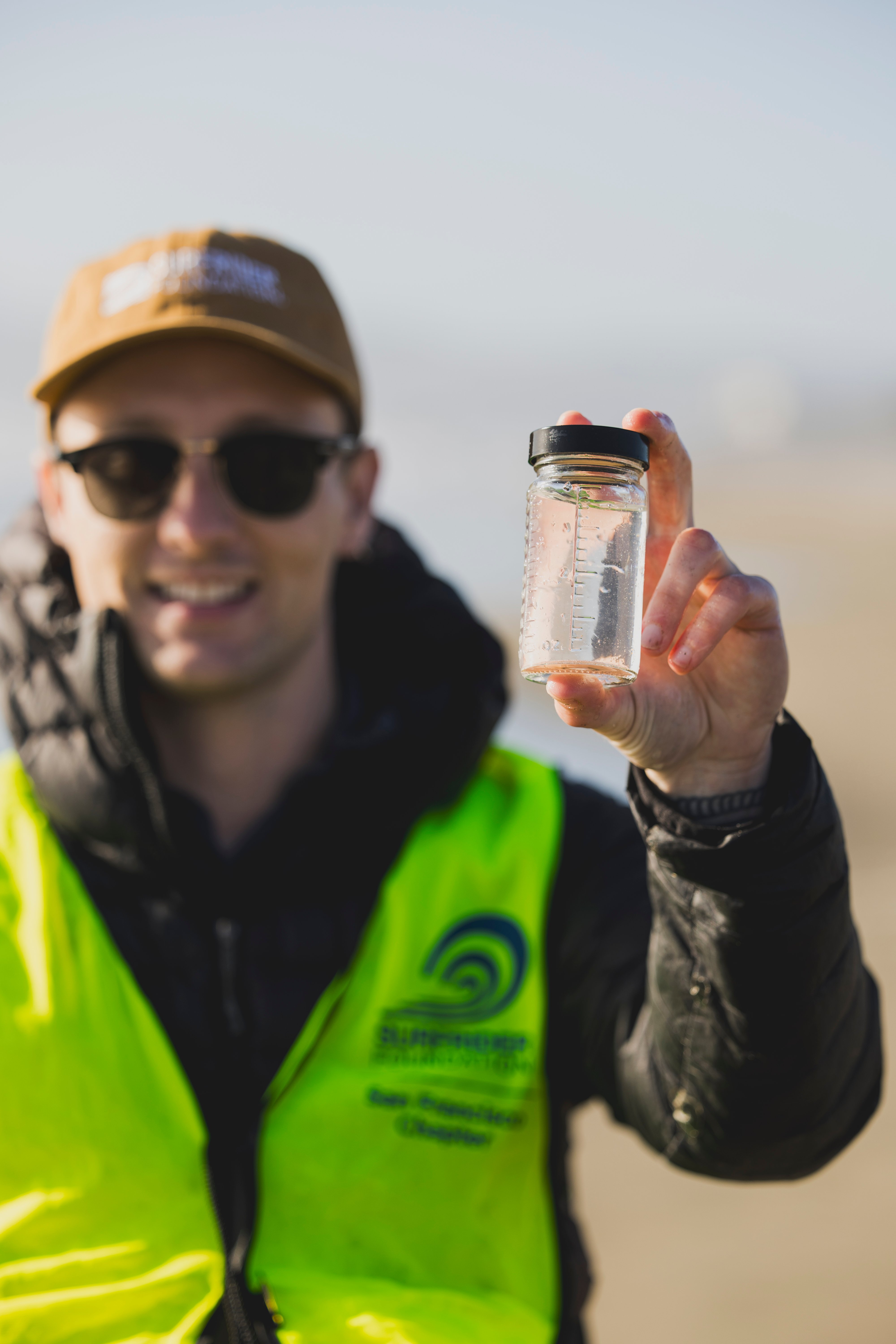 Kyle holds up a water quality sample in a small jar.