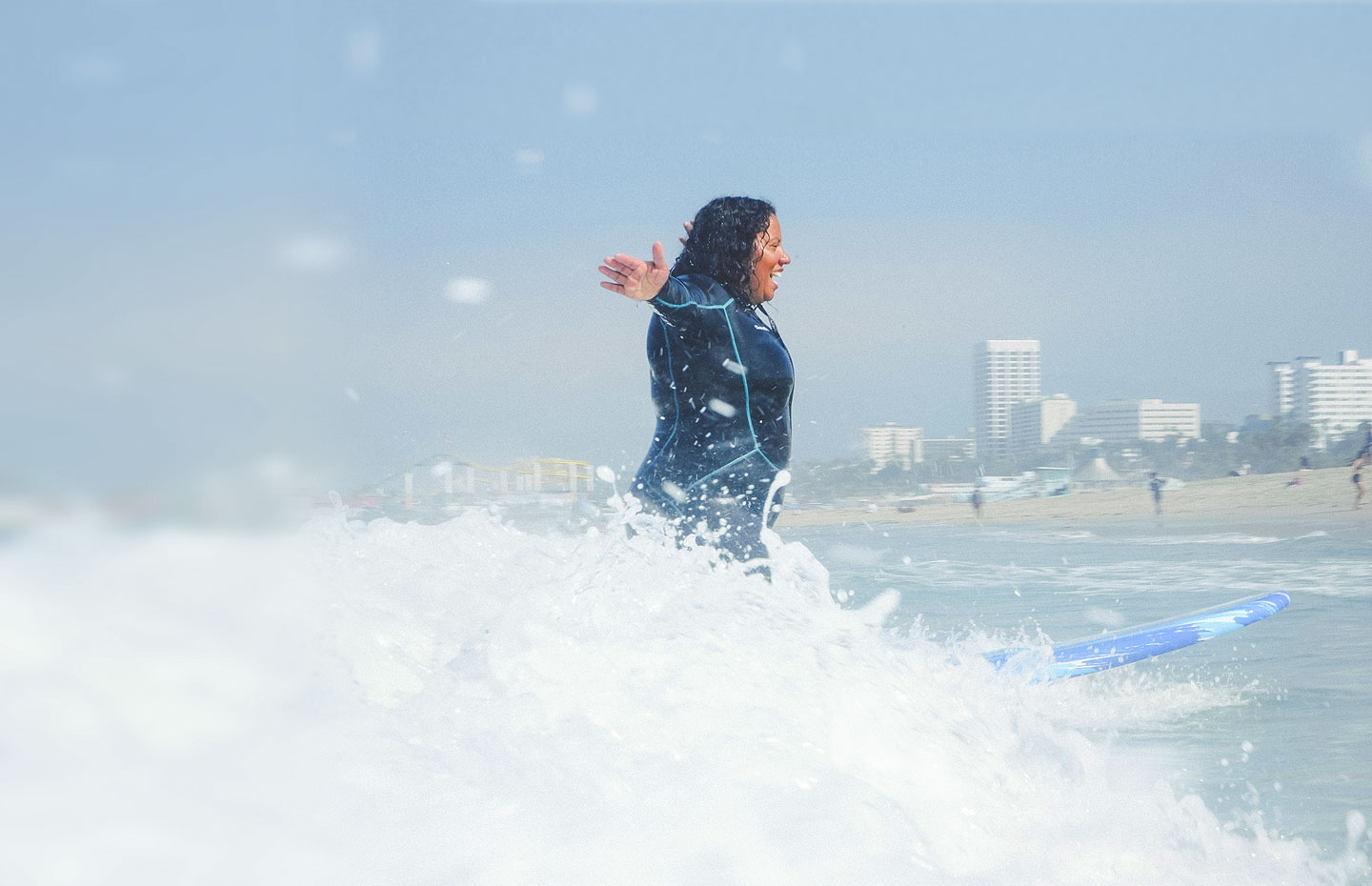 Andrika Payne with the Los Angeles Chapter surfing on a wave smiling