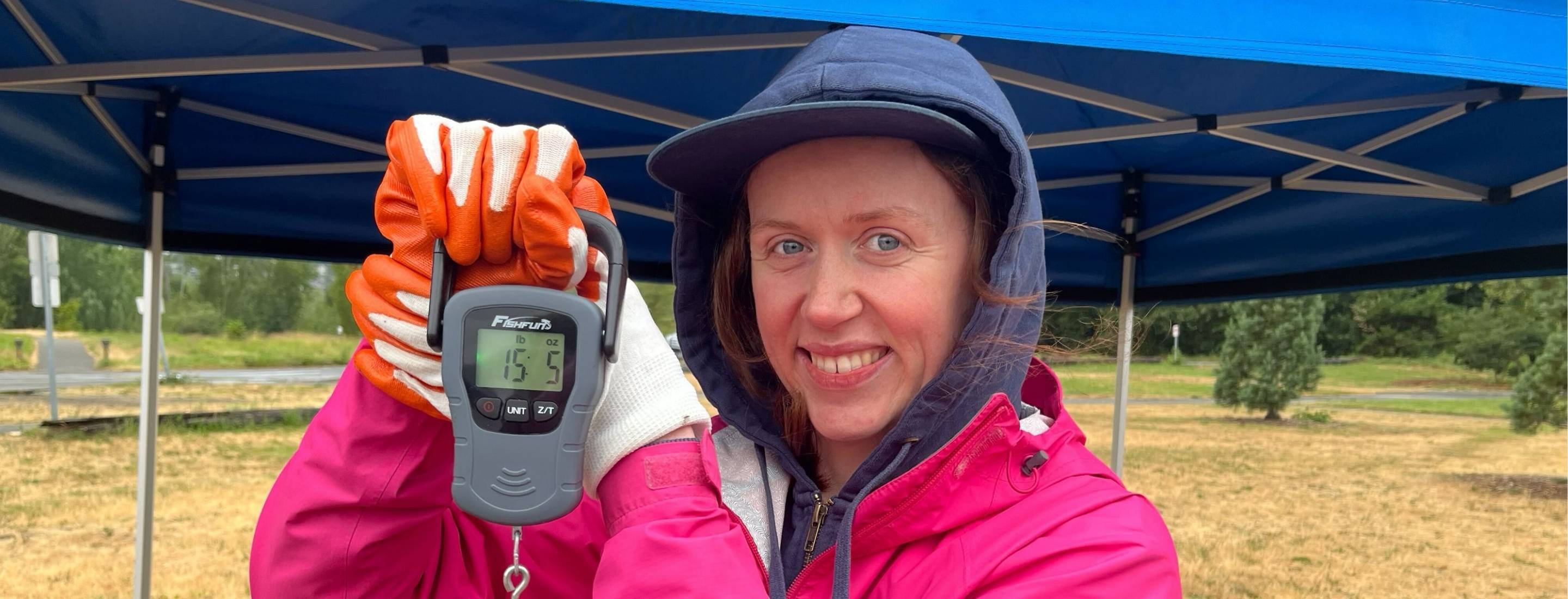 Diana holds a scale with trash that reads 15 pounds, 5 ounces.