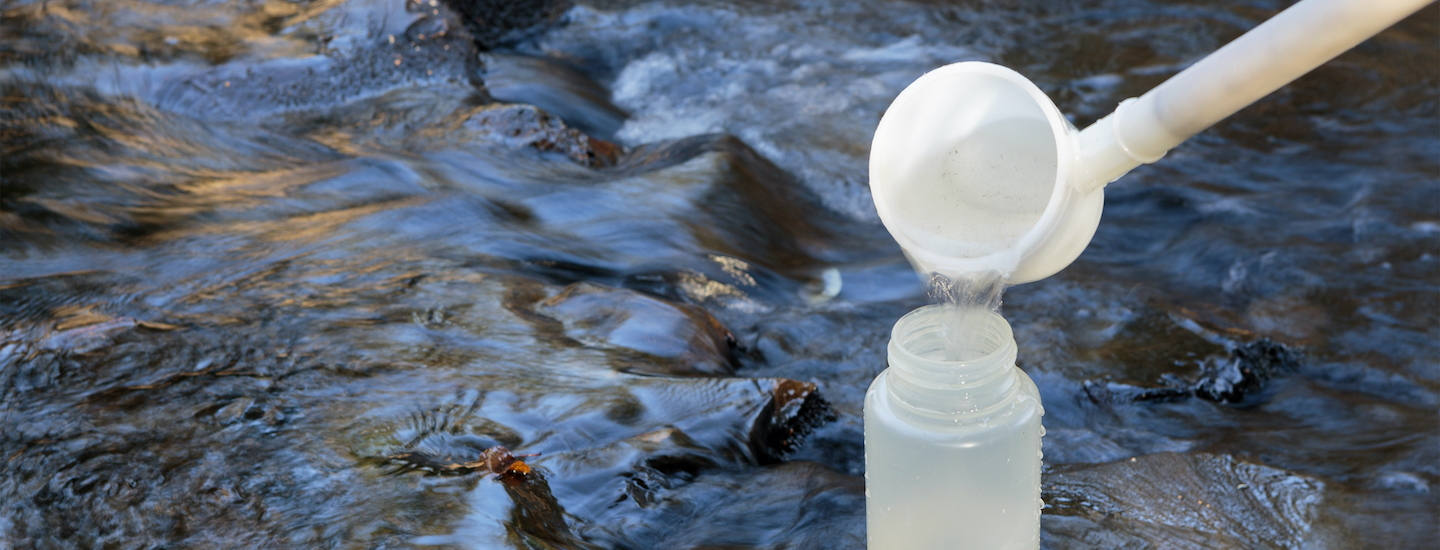 Water sample bottles held just above the waters surface