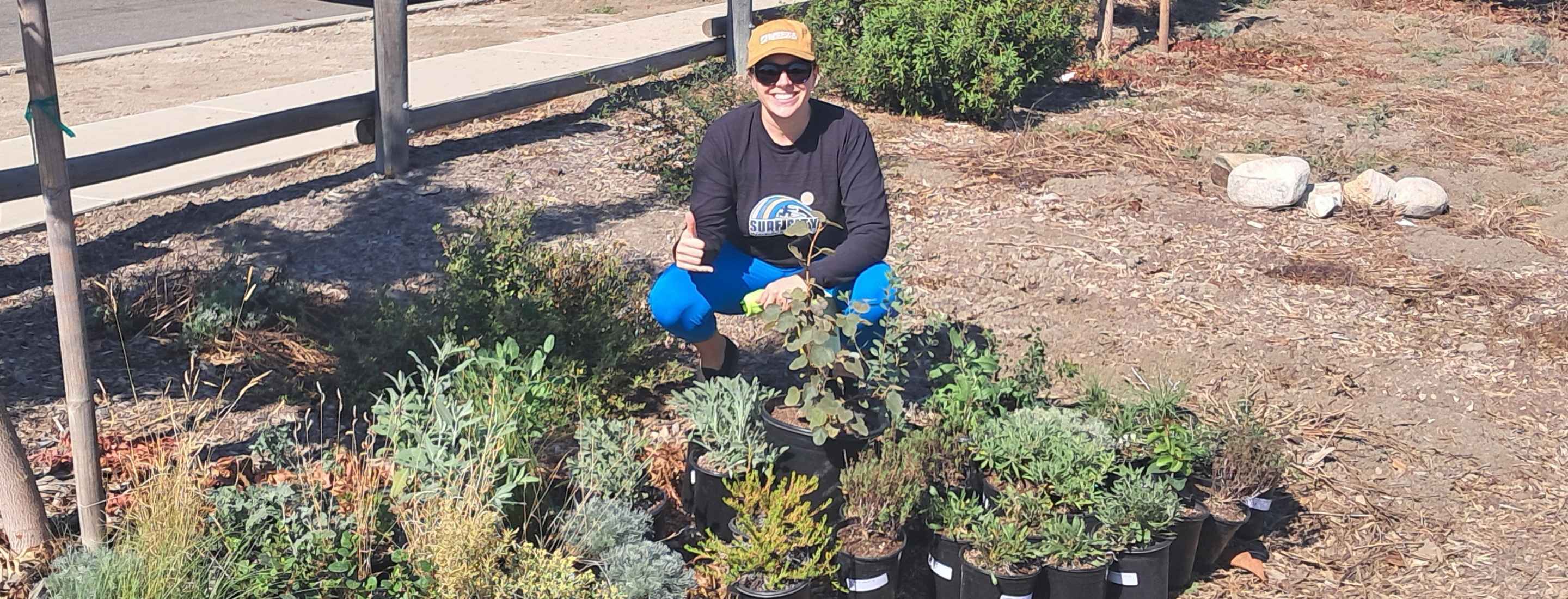 Paige poses in front of plants native to California at an Ocean Friendly Garden.
