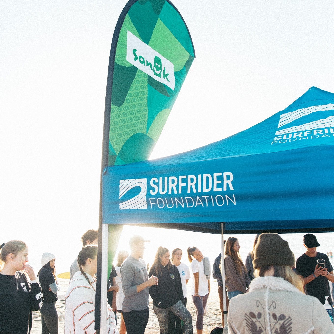 A group of volunteers around a partnership tent A group of volunteers around a partnership tent
