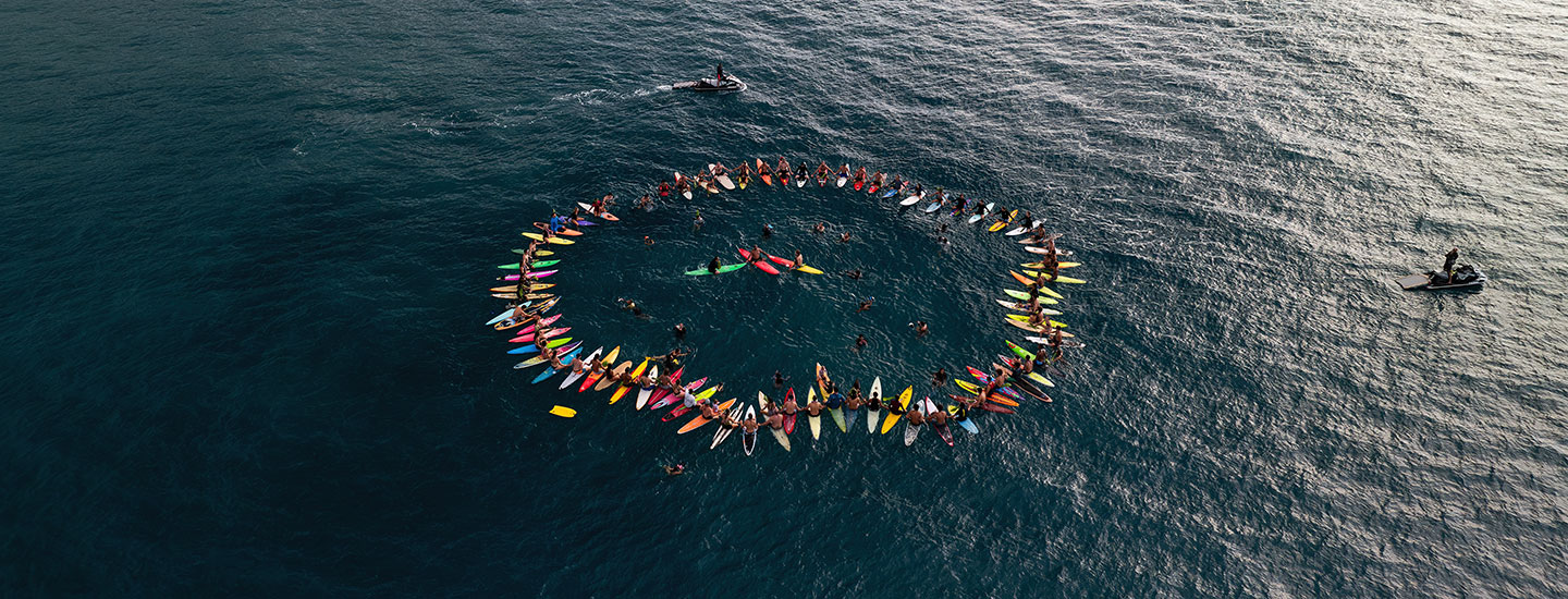 A group of surfers gather in the ocean for a paddle out.